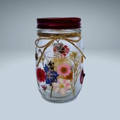 a glass jar filled with flowers on top of a white table next to a red lid