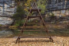 a wooden shelf sitting in the middle of a river next to a rocky cliff face