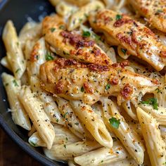 some chicken and pasta in a black bowl