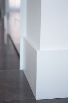 the corner of a room with white walls and tile flooring, as seen from behind