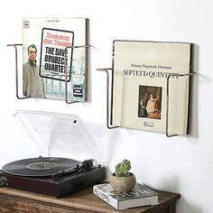 a record player sitting on top of a wooden table next to a wall with posters