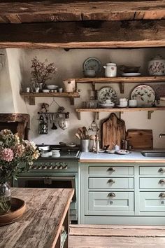 an old fashioned kitchen with green cabinets and wooden shelves on either side of the stove