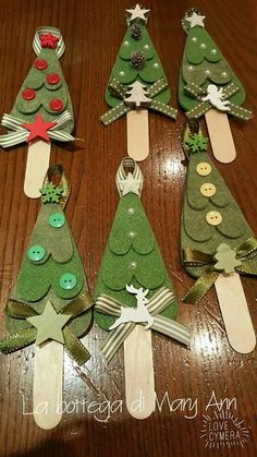 four christmas trees made out of popsicle sticks on a table with buttons and ribbons