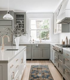 a kitchen with white cabinets and an area rug in front of the stove top oven