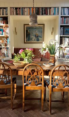 a dining room table and chairs with bookshelves in the background