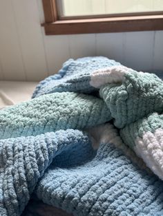 a pile of blankets sitting on top of a bed next to a wooden window sill