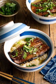 two bowls filled with meat and rice on top of a wooden table next to chopsticks