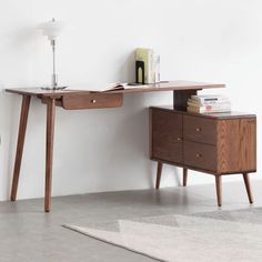 a wooden desk with two drawers and a lamp next to it on top of a rug