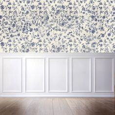 an empty room with white walls and blue flowers on the wall, in front of a wooden floor