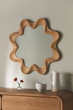 a wooden dresser with a mirror on top of it next to a vase and pitcher