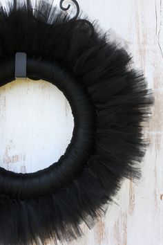 a black tulle wreath hanging on a white wall