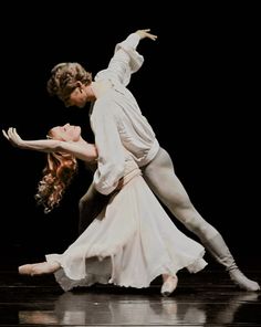 two dancers in white are performing on stage