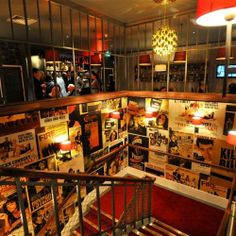 a stairwell with posters on the wall and lights hanging from it's ceiling above