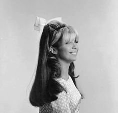 a black and white photo of a woman with long hair wearing a bow in her hair