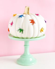 a painted pumpkin sitting on top of a cake plate