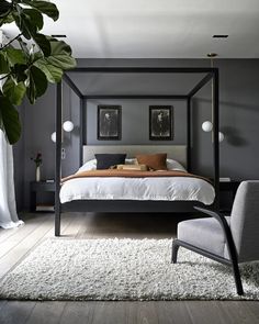 a bedroom with a four poster bed, chair and rugs on the hardwood floor