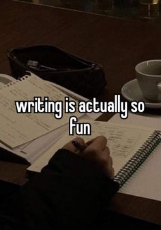 someone writing is actually so fun on their desk with a cup of coffee and notebook