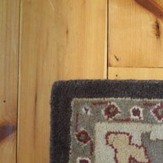 a cat laying on top of a rug next to a wooden floor with a door handle