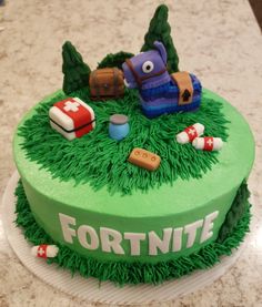 a cake with green frosting that says fortnite on it and various items