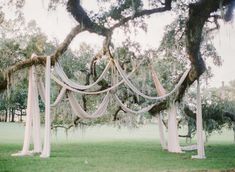 an outdoor wedding ceremony setup with draping and draped fabric on the tree branches