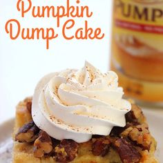 pumpkin dump cake on a white plate with whipped cream and pecans in the background