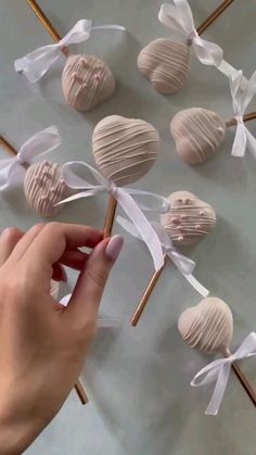 a person holding some candy sticks in front of several heart shaped lollipops