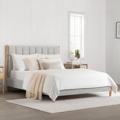 a bed with white sheets and pillows in a room