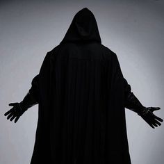 a person in a black robe and gloves with their hands out to the side,