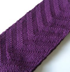 a purple knitted tie laying on top of a white table