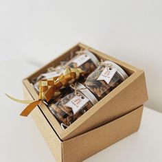 an open box filled with cookies on top of a white table next to a brown ribbon