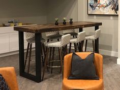 a living room filled with furniture and a wooden table surrounded by bar stools next to a kitchen