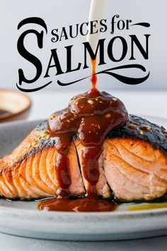 salmon being drizzled with sauce on top of it and sitting on a plate