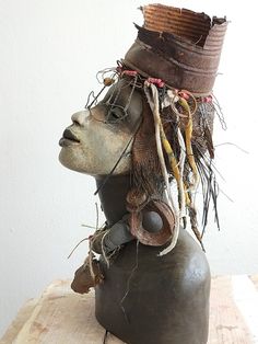 a clay head wearing a hat with hair on it's head and wire attached to the top