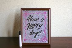 there is a small frame with writing on it and a pen next to it that says have a happy day