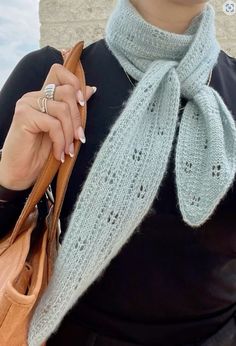 a woman wearing a gray scarf and holding a brown purse