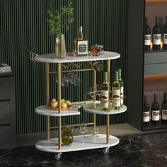 three tiered bar cart with bottles and glasses on it in front of a green wall