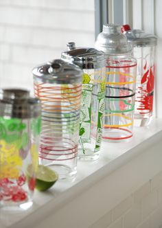 the cups are lined up on the window sill with limes and lemon wedges