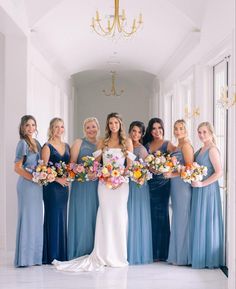 a group of women standing next to each other in front of a chandelier