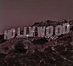 the hollywood sign is lit up on top of a hill with trees in the background