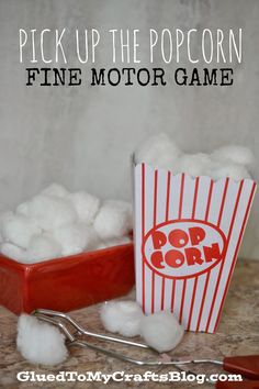 a red bucket filled with cotton next to a pile of popcorn