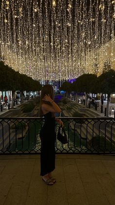 a woman standing in front of a fence covered with lights