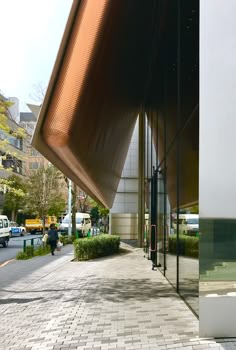 a woman walking down a sidewalk next to a tall building