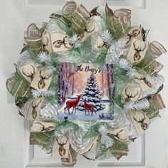 a christmas wreath with an image of a deer and a pine tree on the front door