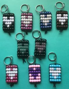 six key chains made out of beads on a blue surface, with one bead in the shape of a square