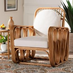 a wicker chair with white cushions in a living room area next to a potted plant