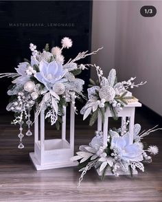 two white vases filled with flowers sitting on top of a wooden floor next to each other