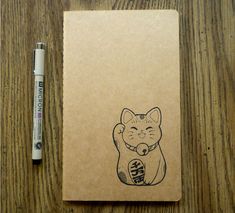 a notepad with a drawing of a cat on it next to a marker pen