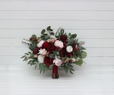 a bouquet of red and pink flowers on a white background with greenery in the center