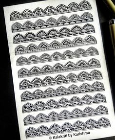 a notebook with black and white designs on it next to a pen, pencil and paper