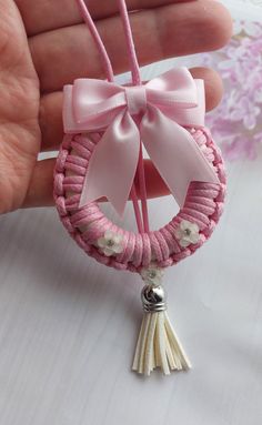 a hand holding a pink and white beaded keychain with a bow on it